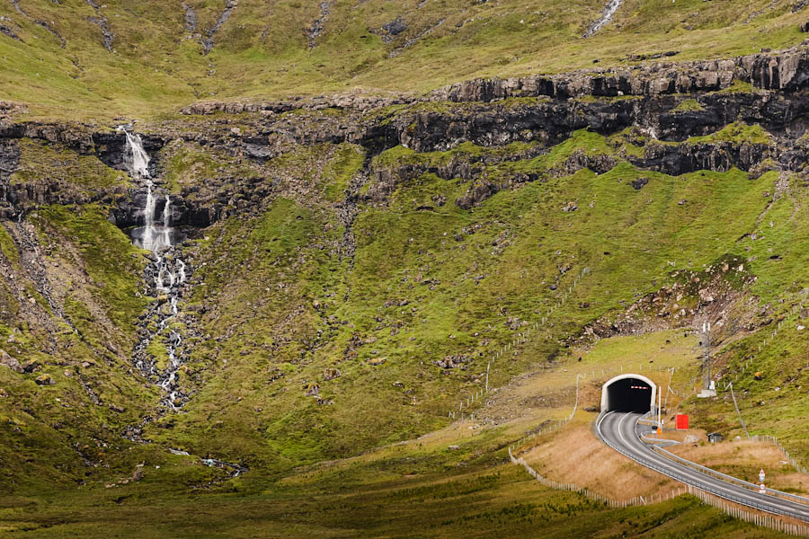 Faroe islands mountain tunnel entrance and green landscape with waterfall